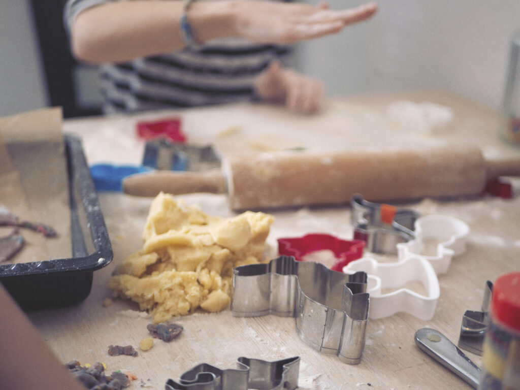 Christmas Chaos: Baking Supplies And Little Girl Forming Cookie Dough In Background