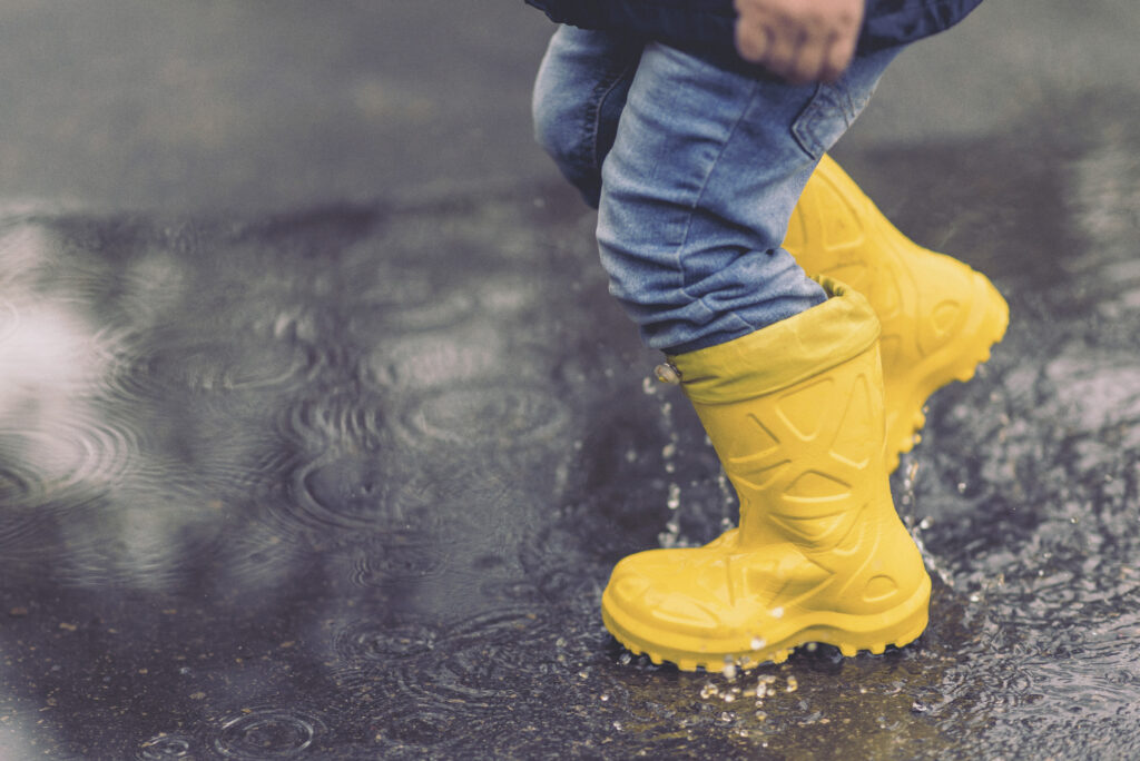 little boy walks through the puddles in the spring after the rain