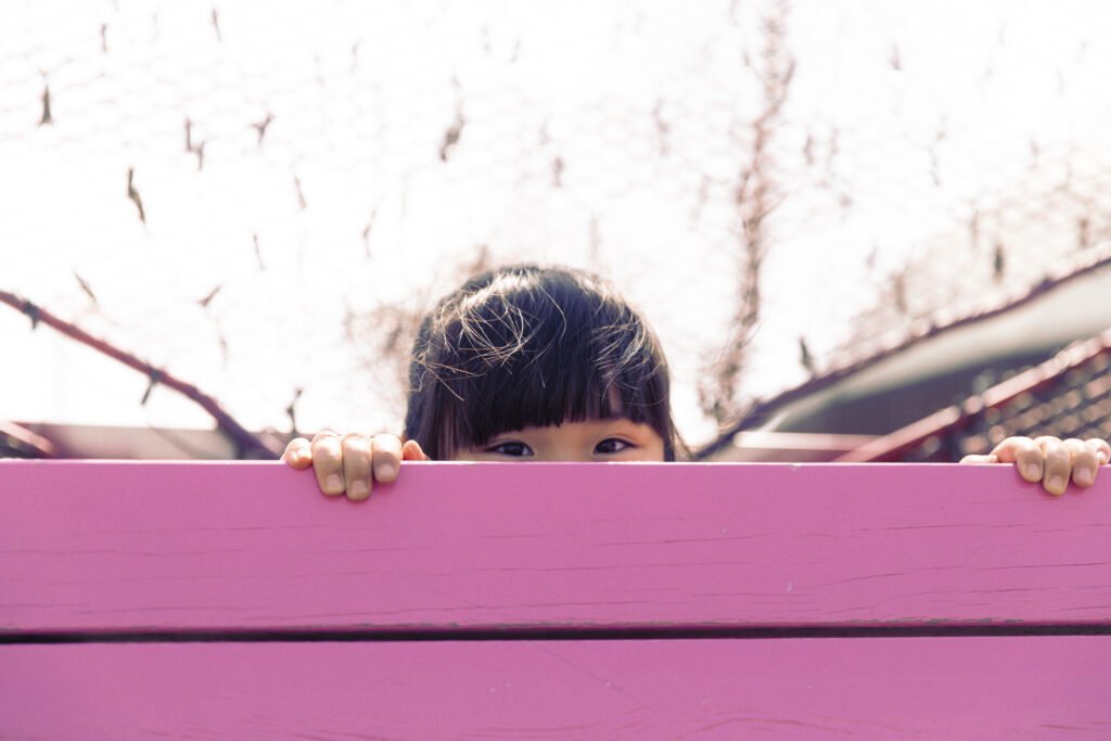Little girl hiding behind pink board