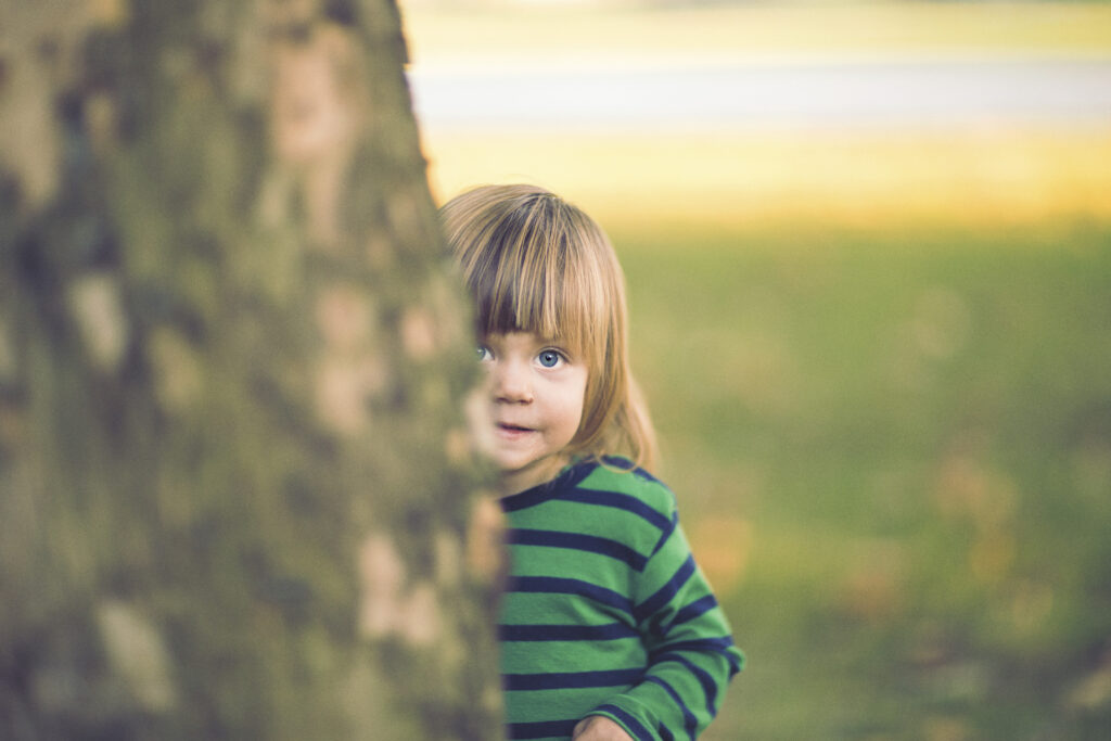 Little boy hiding behind the tree