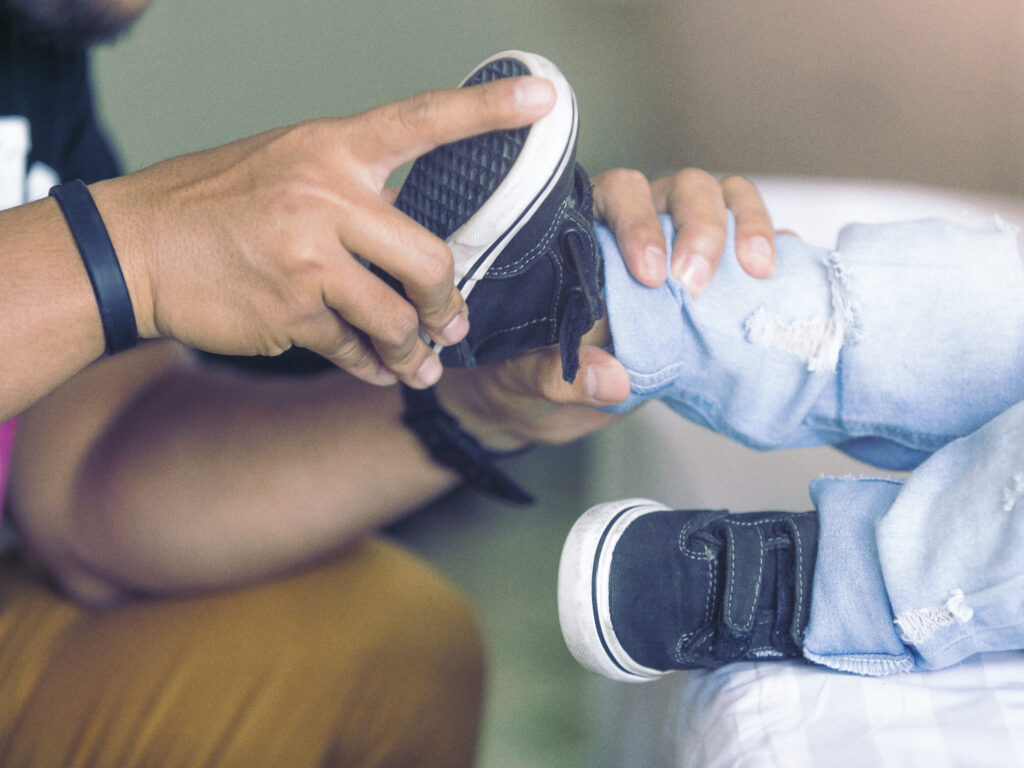 Father is helping his son to tie his shoes
